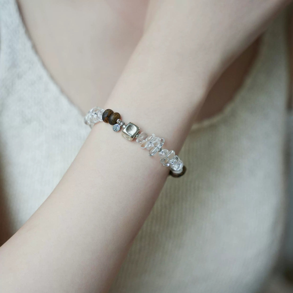 Pine clear quartz bracelet with silver-tone cube worn on the wrist