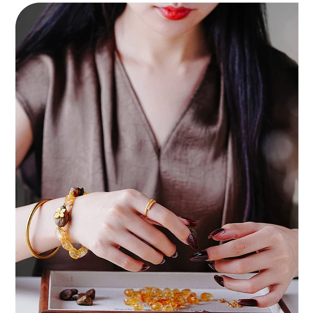 Model wearing the Tingchao citrine and agarwood bracelet at a jewelry tray