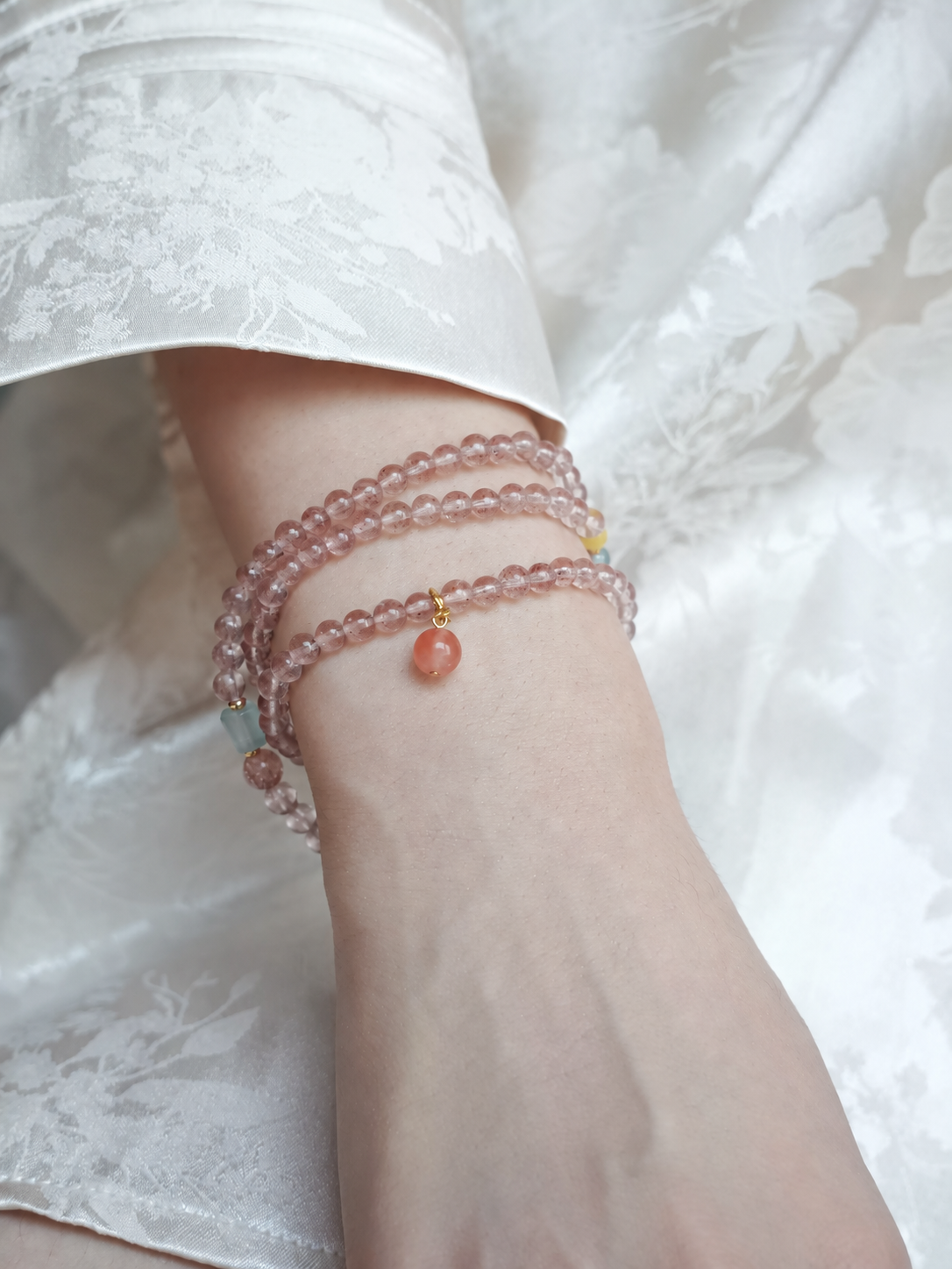 Cloud Weave strawberry quartz three-wrap bracelet worn on wrist
