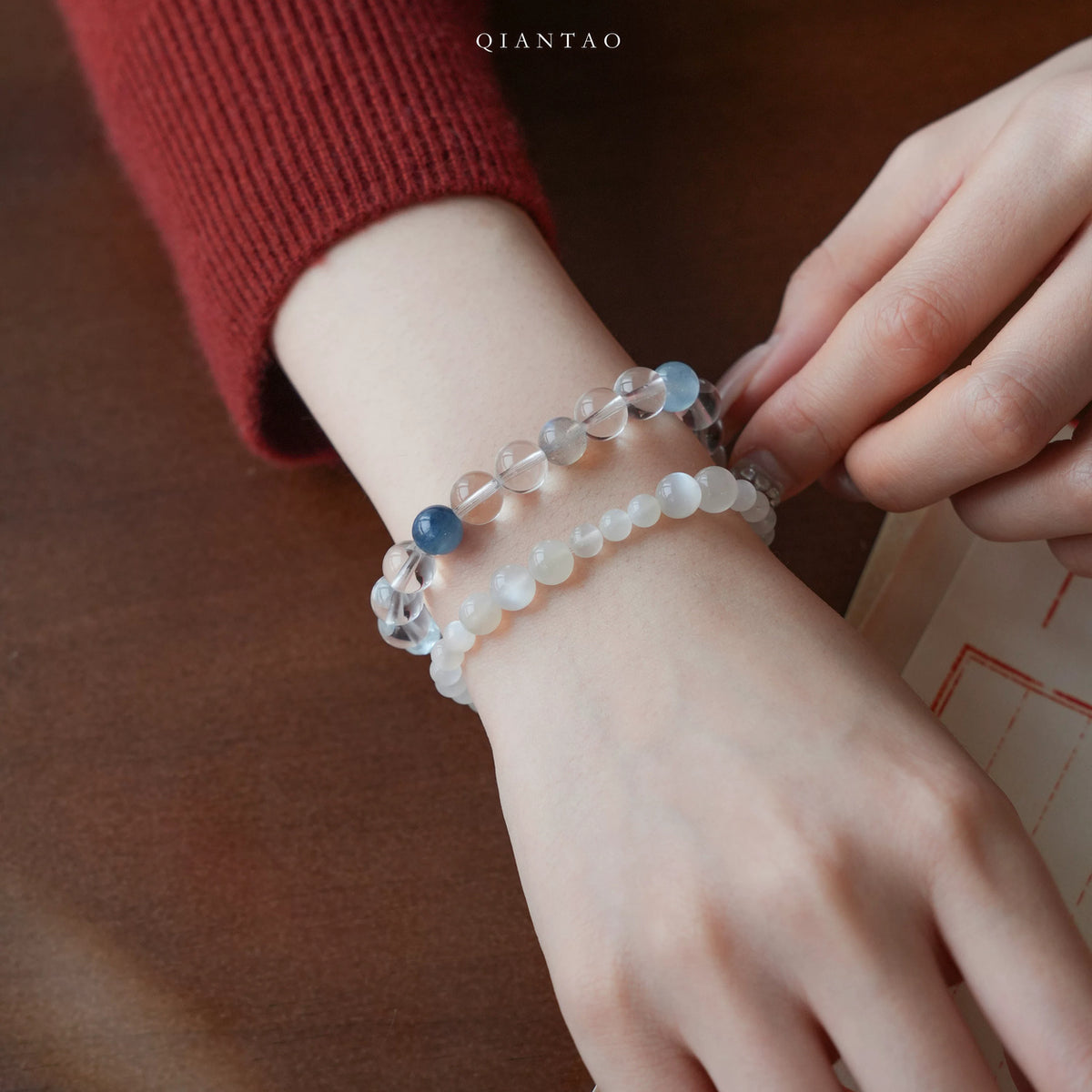 Tide clear quartz bracelet styled on the wrist with a red knit sleeve