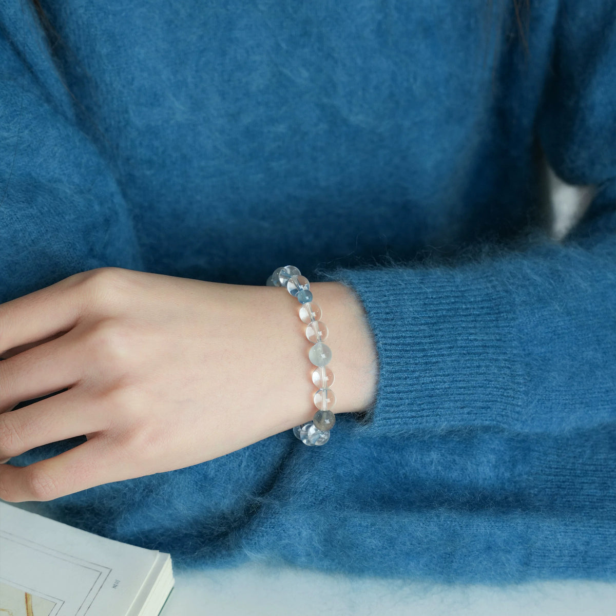 Tide clear quartz and blue gemstone bracelet worn with a blue knit sweater