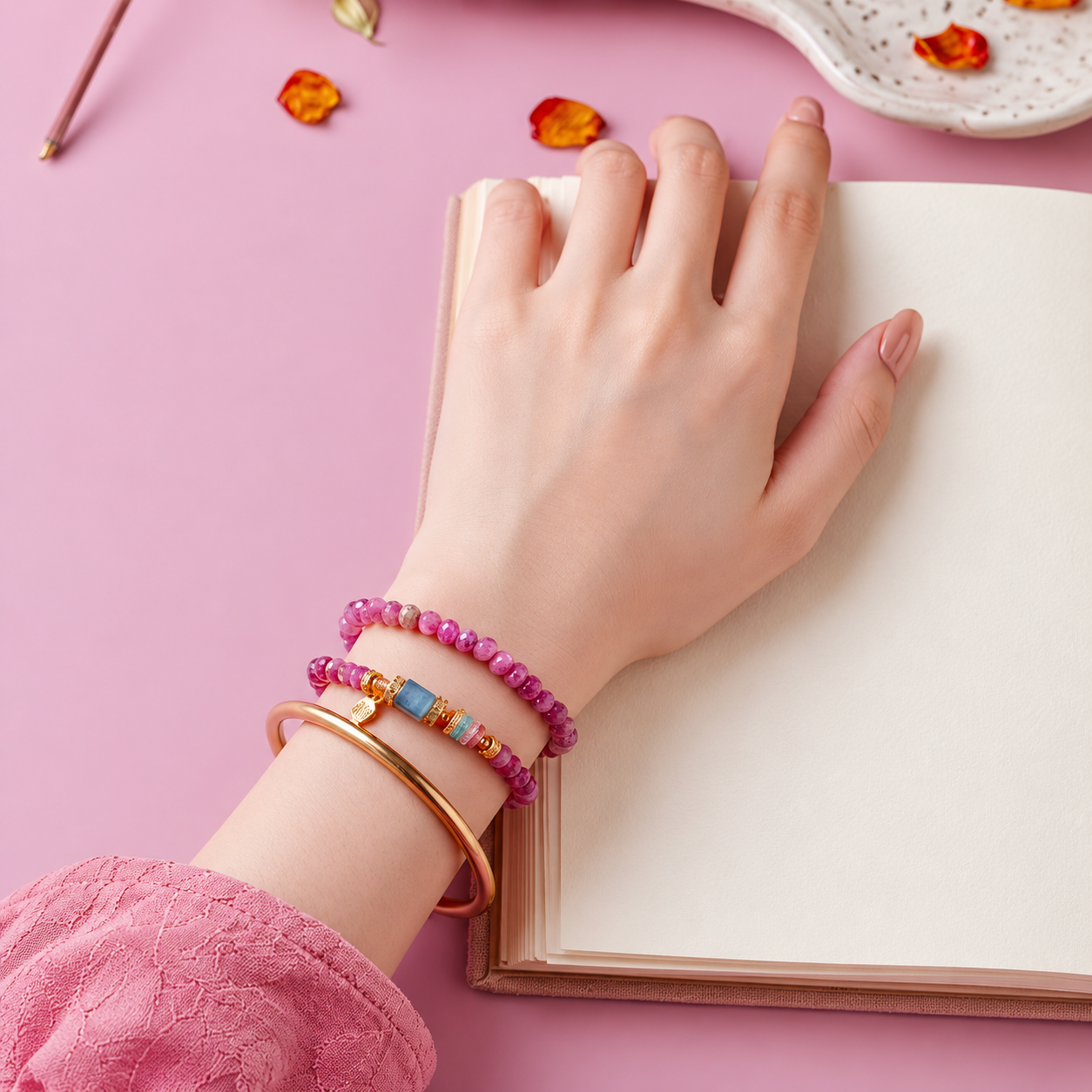 Pink tourmaline crystal bracelets worn beside an open book