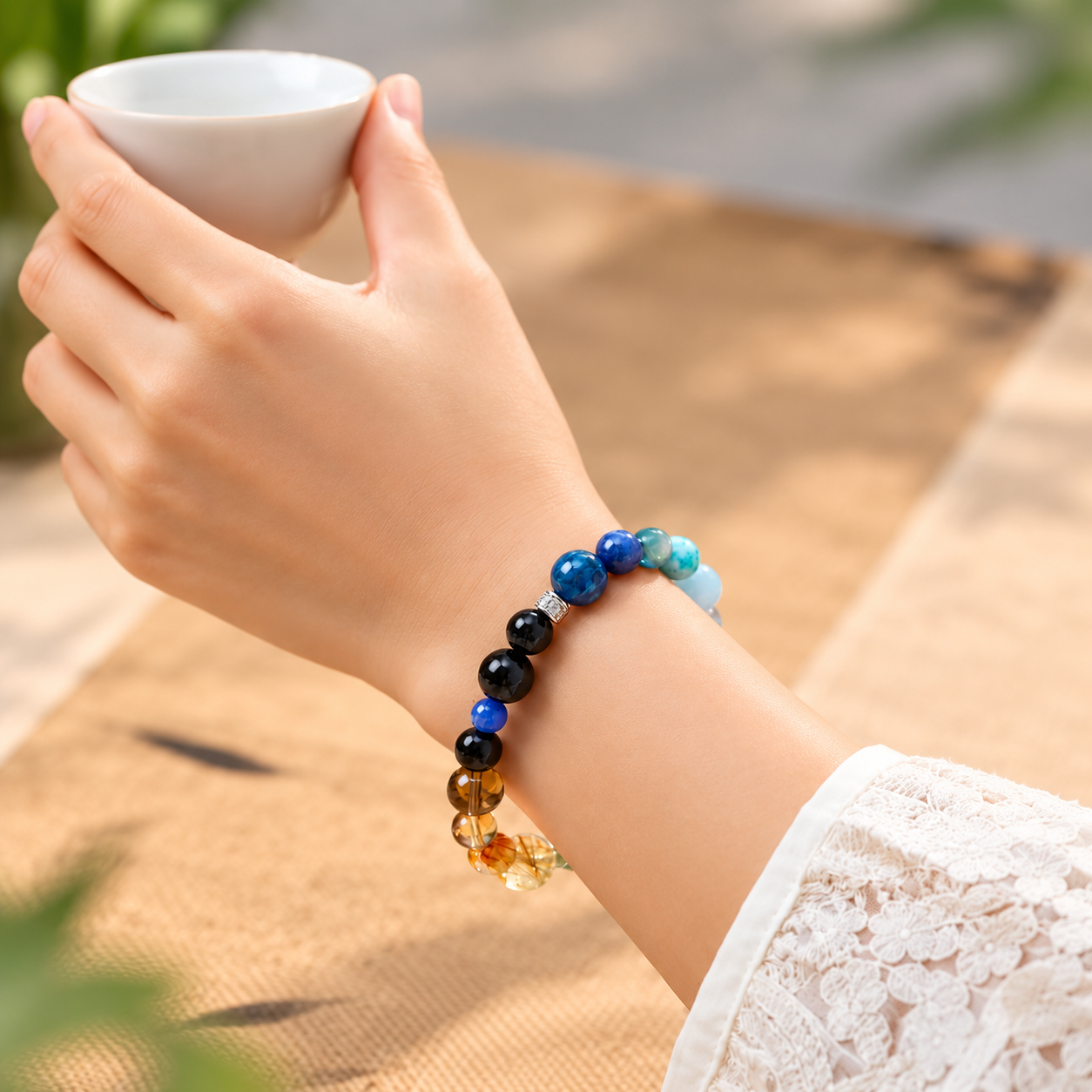 Five Elements crystal bracelet worn while holding a tea cup